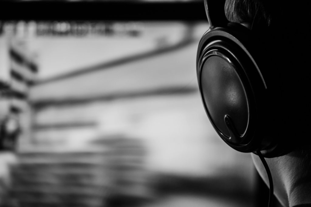 Black and white image of a person listening with headphones, conveying focus and immersion.